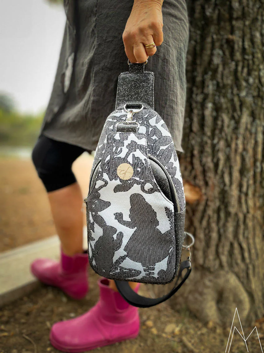 Photo of a mature woman carrying a gray and blue backpack by hand, in an outdoor park during the day.