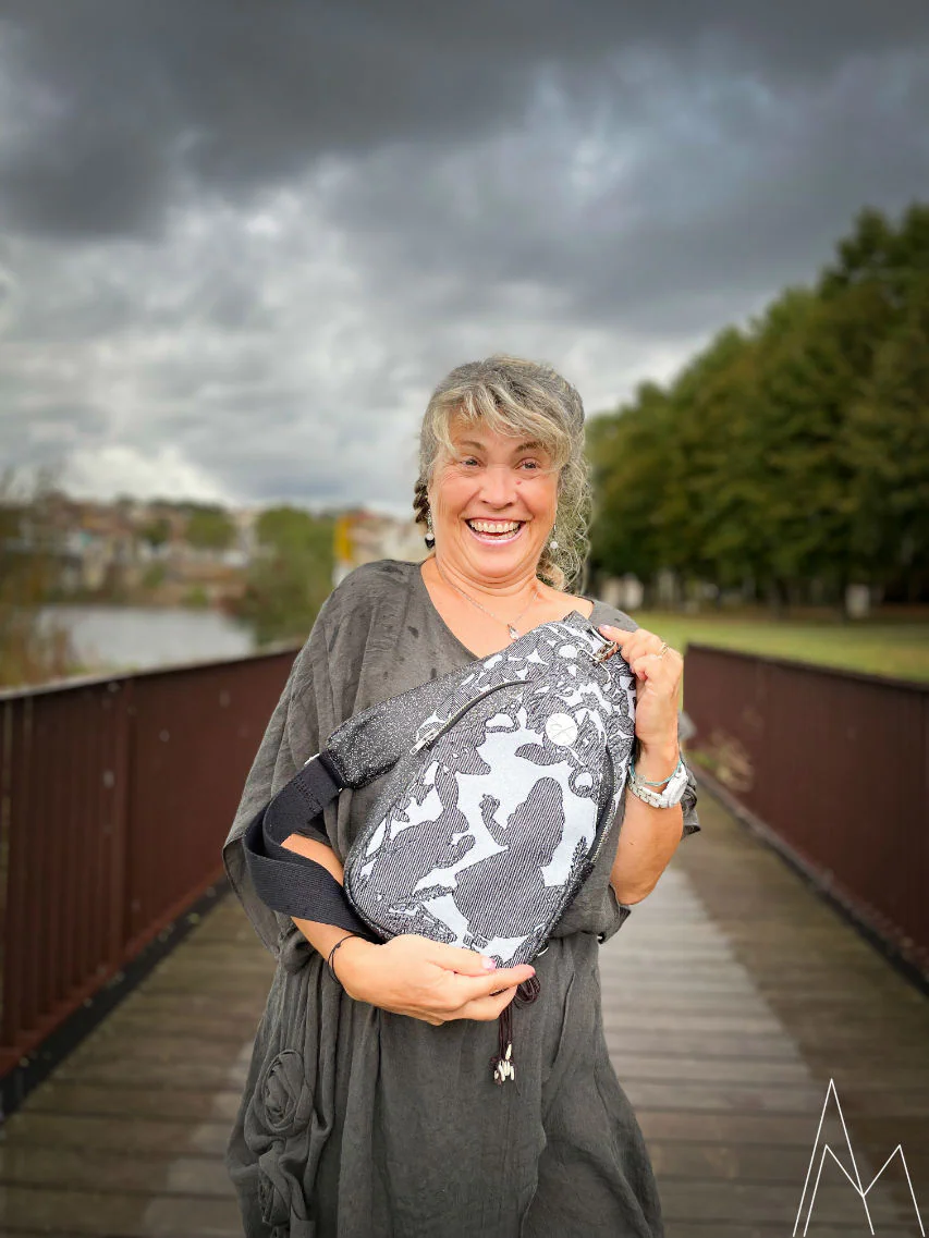 Photo of a mature woman carrying a gray and blue backpack, in an outdoor park during the day.