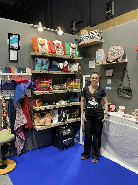 Marie Alhomme at her stand at the Salon du Made in France 2024 — leatherwork pieces and accessories displayed on wooden shelves.