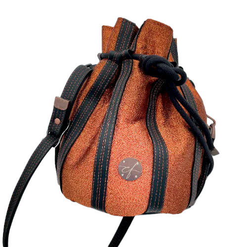 A shiny “bucket” bag made with shiny bronze fabric outlined by butter smooth matte black faux leather.