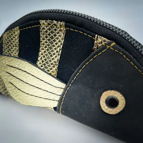 A zippered pouch sewn with black cork, black voile with golden stripes, and golden metallic leather.