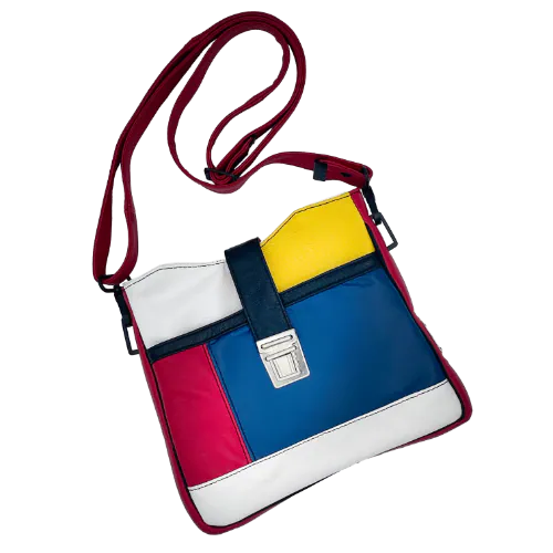 A crossbody bag made of different leathers in royal blue, deep red, bright yellow, white, and black.