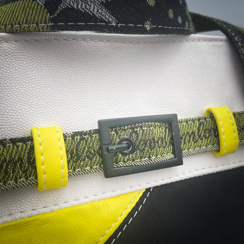 A long, low bag made from yellow, white and black leather and a wrap fabric with a floral pattern in black, yellow and white, lined with yellow canvas.