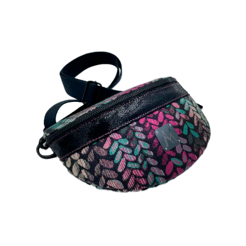 A fanny pack sewn from black patent leather and a scrap of baby wrap fabric with a pattern of green, beige, and pink stitches on a black background, paired with bright pink poplin lining inside.