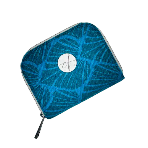 A zipped card-and-coin wallet made with a piece of babywearing wrap fabric featuring forest green and turquoise leaf patterns with glitter accents.
