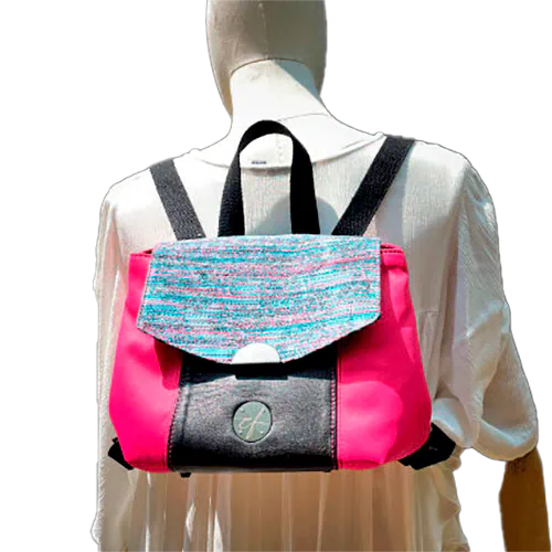 A backpack made with bright pink upholstery fabric, black leather, and wrap fabric with a floral pattern.