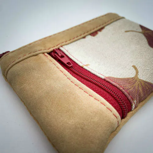 A mini zippered coin purse made of camel colored leather and a red Ginkgo Biloba leaves patterned polycotton canvas.