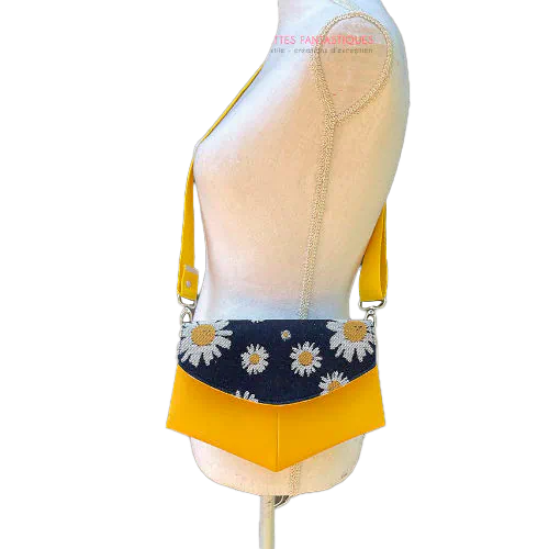 A small bag made from yellow faux leather and a fabric coupon with white and yellow daisies on a navy blue background.