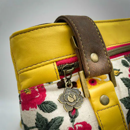 A shoulder bag made from chocolate and yellow leathers combined with a floral canvas featuring pink and yellow flowers.