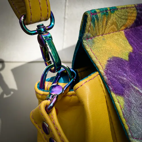 An angular bag made from yellow leather and a hand-painted damask fabric, lined with turquoise and violet satins.