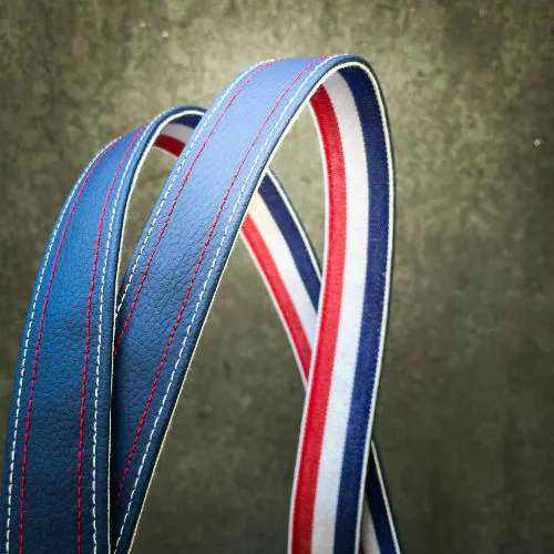 A shoulder bag made with several babywearing wrap coupons (blue, white, and red) and white and blue faux leather.