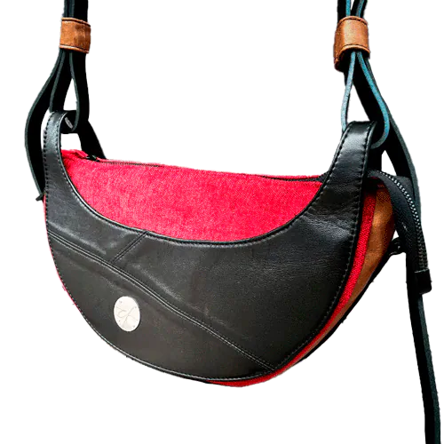A shoulder bag made of black and caramel leathers, red and black velvet upholstery fabric, and red and black satins.