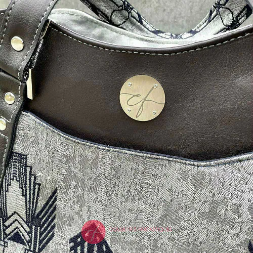 A shoulder bag made with midnight blue and silver geometric Art Deco wrap fabric, and midnight blue leather.