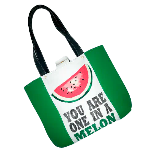A large bag made from green leather on the outside and a canvas printed with a fruit design with an English pun underneath, and on the inside a forest green poplin.
