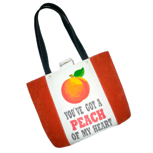 A large bag made from orange leather on the outside and a canvas printed with a fruit design and English wordplay underneath, with an iridescent orange viscose interior.
