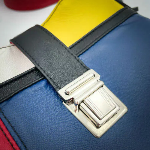 Un sac besace composé de différents cuirs bleu roi, rouge profond, jaune vif, blanc et noir.