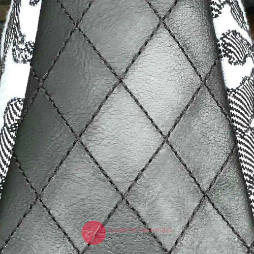 Un sac en bandoulière trapézoïdal fabriqué à partir d'une écharpe de portage “Alice au pays des merveilles” en noir, bleu-gris et argent, associée à un simili noir matelassé à la main.