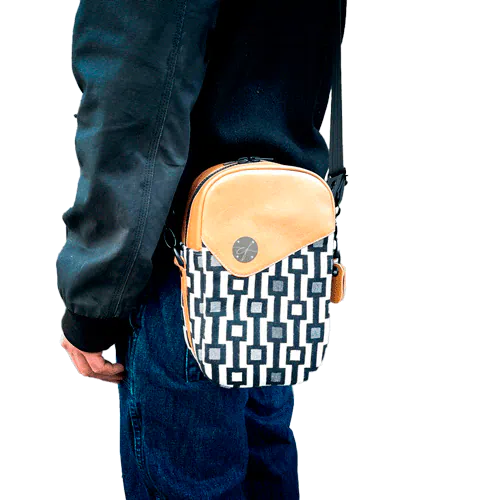 Un sac en bandoulière fabriqué à partir d'une écharpe de portage à motif géométrique noir et blanc, de cuir caramel et de popeline rouge.