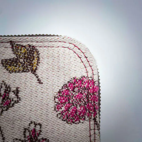 Un petit porte-cartes et monnaie zippé fait avec du tissu d'écharpe au motif floral dans les tons roses sur fond écru et du liège brique.