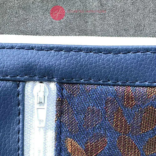 Un mini porte-monnaie zippé composé d'un patchwork de différents matériaux : simili bleu royal, simili doré, tissu bronze brillant et tissu d'écharpe de portage bleu et bronze avec un motif de petites gouttes.