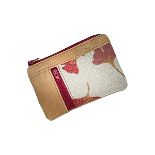 Un mini portemonnaie zippé fait de cuir de couleur camel et d'une toile en polycoton avec un motif de feuilles de Ginkgo Biloba rouges.