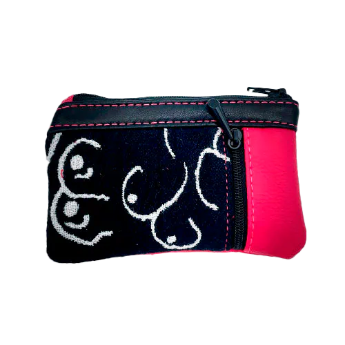 Un petit porte-monnaie zippé fabriqué à partir d'un patchwork de différents matériaux : une écharpe de portage noir et blanc avec un motif stylisé de seins, du cuir d'agneau noir et du simili fuchsia.