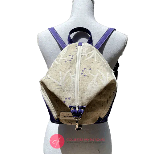 Un sac à dos confectionné en neoprene violet et en tissu d'écharpe dans des tons écru et violet, au motif d'oiseaux dans des branches.