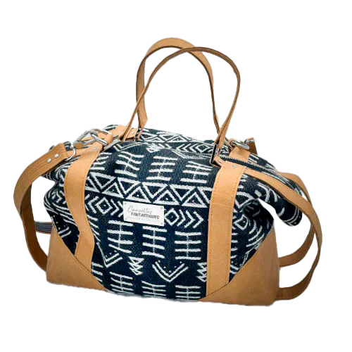 Un petit sac de voyage fabriqué en papier lavable couleur caramel, une écharpe de portage à motif géométrique noir et blanc, et de la popeline grise.
