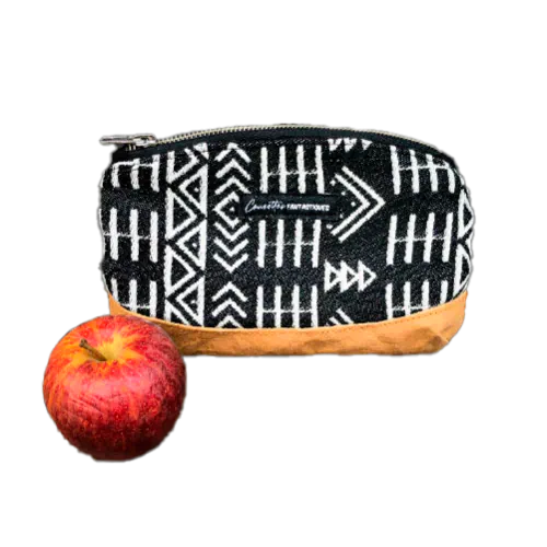 Une petite pochette zippée fabriquée en papier lavable coloris caramel, une écharpe de portage à motifs géométriques en noir et blanc, et de la popeline grise.