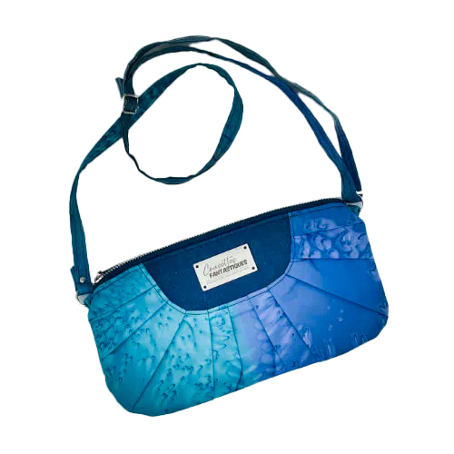 Une pochette zippée cousue dans un foulard en soie dans les tons bleus, plissé et associé à du liège bleur roi.