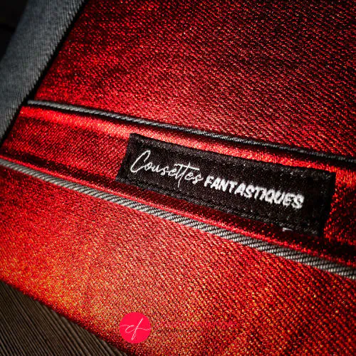 Une pochette zippée cousue dans un denim bi-face gris et rouge métallisé, associé à de la soie rouge vif.
