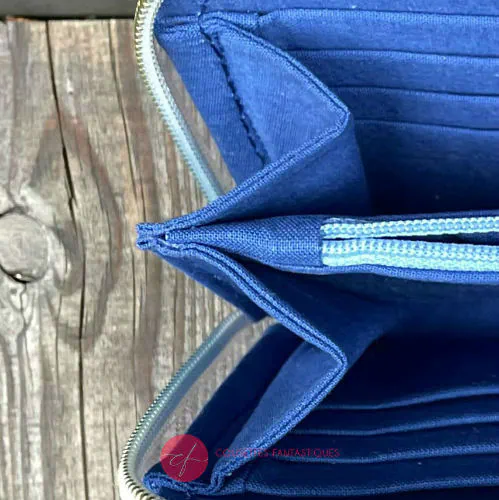 Un porte-cartes-et-monnaie zippé fabriqué avec une écharpe de portage à dégradé arc-en-ciel avec un motif d'étoiles pointillistes et du jean de haute couture gris.