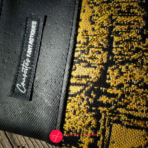 Un porte-cartes-et-monnaie zippé fabriqué avec un coupon d'écharpe de portage marbré noir et or et du liège noir mat.