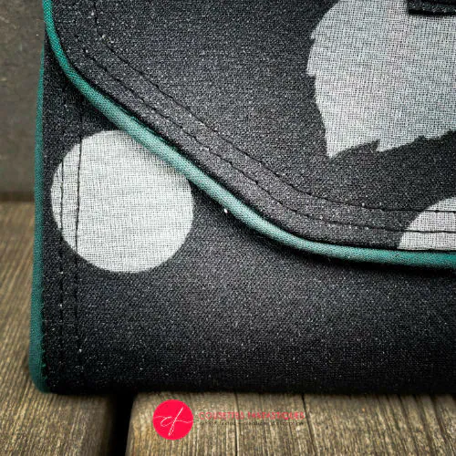 Un portefeuille fait de foulard de soie à fleurs noires et blanches à l'extérieur et de popeline noire à l'intérieur.