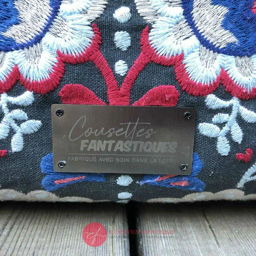 Un sac cabas en tissu gris brodé de motifs floraux scandinaves bleus, rouges et blancs, en gabardine rouge et en popeline bleu roi.