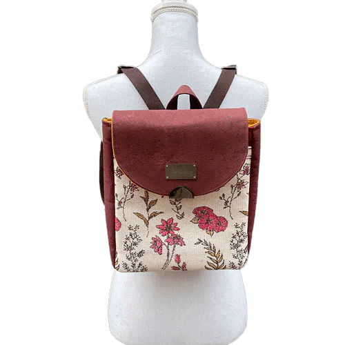 Un sac à dos fabriqué avec un tissu d'écharpe à motifs floraux dans des tons roses sur fond écru et en liège couleur brique.
