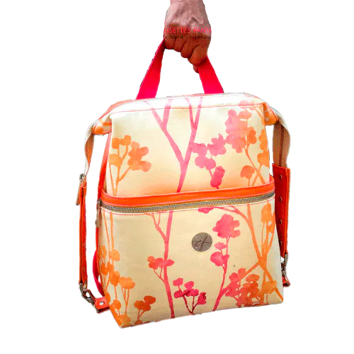 Un sac à dos confectionné en simili orange vif et en tissu d'ameublement crème au motif végétal dégradé de rose à orange.