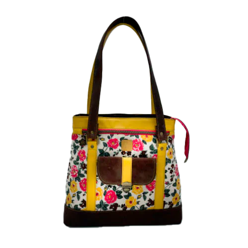 Un sac d'épaule fabriqué à partir de cuirs chocolat et jaune mariés à une toile fleurie avec des fleurs roses et jaunes.