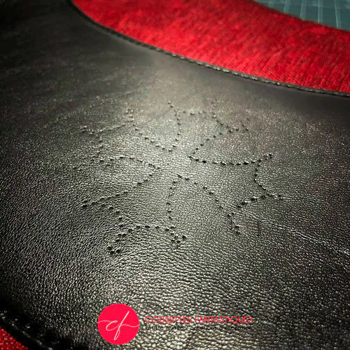 Un sac à bandoulière en cuir noir et caramel, tissu d'ameublement en velours rouge et noir, et satins rouge et noir.