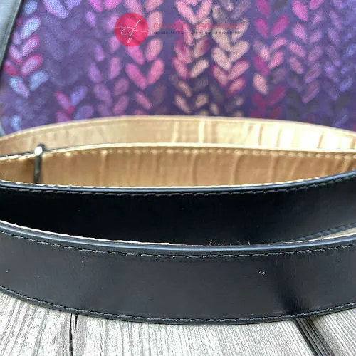 Un sac d'épaule fait en tissu dans les tons violets, pourpres, roses... au motif de goutelettes, et de cuir d'agneau noir upcyclé.