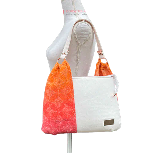 Un sac d'épaule fait avec du tissu d'écharpe dégradé de jaune orangé à rose, au motif motif étoiles pointillistes, et du simili blanc.