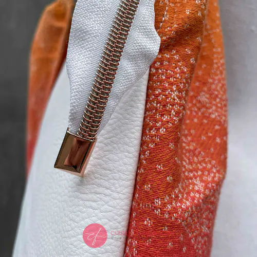 Un sac d'épaule fait avec du tissu d'écharpe dégradé de jaune orangé à rose, au motif motif étoiles pointillistes, et du simili blanc.