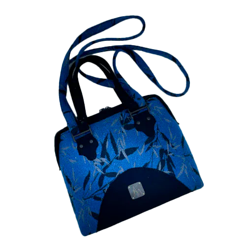 Un sac d'épaule confectionné à partir d'écharpe de portage au motif de bambous noir et bleu roi, d'un drap de laine bouillie noire et d'un cuir texturé à paillettes, couplés à un satin gris bleuté à l'intérieur.