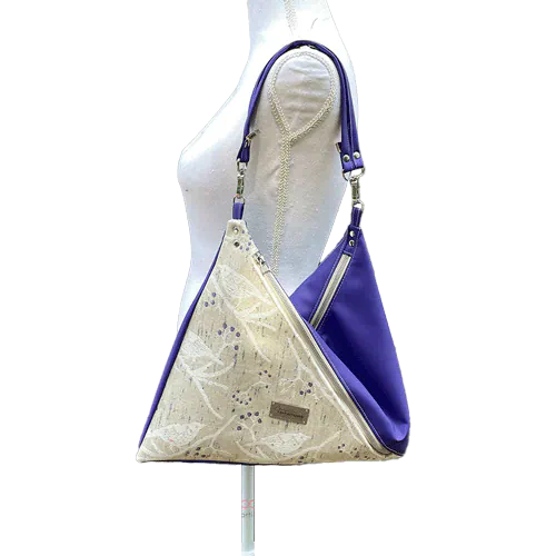 Un sac d'épaule triangulaire en simili beige et tissu d'écharpe de portage blanc, crème, beige et vert.