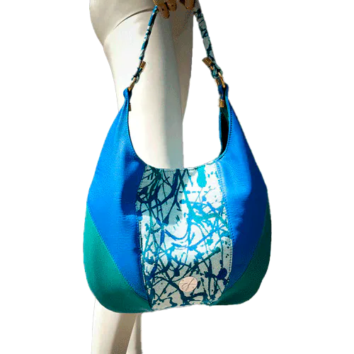 Un sac d'épaule en cuirs bleu royal et vert sauge, écharpe de portage blanc, bleu et vert avec un motif organique, et popeline vert sapin.