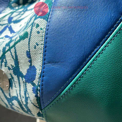 Un sac d'épaule en cuirs bleu royal et vert sauge, écharpe de portage blanc, bleu et vert avec un motif organique, et popeline vert sapin.
