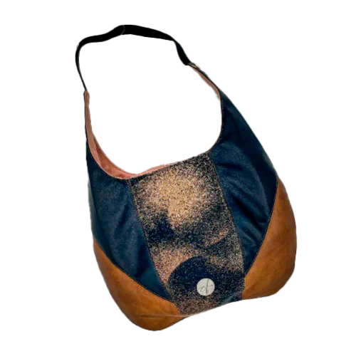 Un sac d'épaule en cuirs marron et noir, écharpe de portage noir, marron et beige avec un motif abstrait rond, et toile de lin pêche.