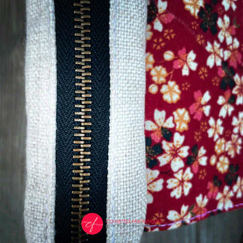 Un sac de hanche constitué de toile grossière écru au motif géométrique noir de signes plus et d'une popeline fleurie dans les tons rouge, noir, blanc et jaune.