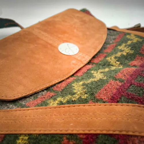 Un sac de taille moyenne, porté épaule, main, bandoulière ou dos, en suédine alezan et drap laine au motif géométrique, avec une doublure en viscose molletonée motif géométrique.