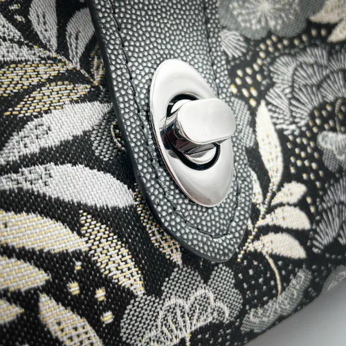 Un mini sac à main constitué de tissu d'ameublement noir, blanc, gris et doré, et de cuir anthracite et argenté.